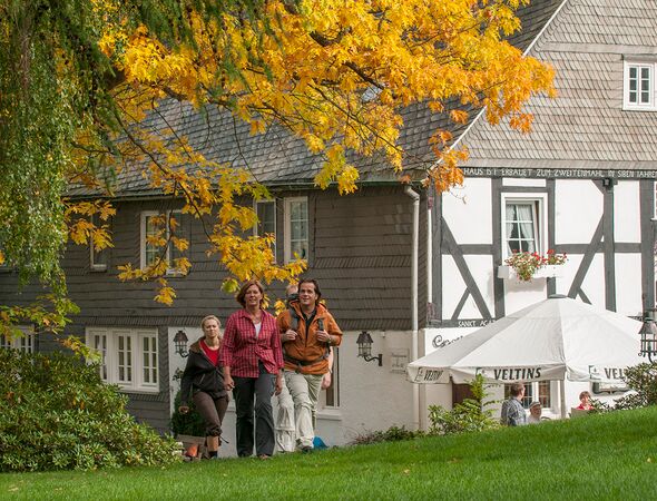 Huis en boomtak met herfstbladeren en wandelgroep