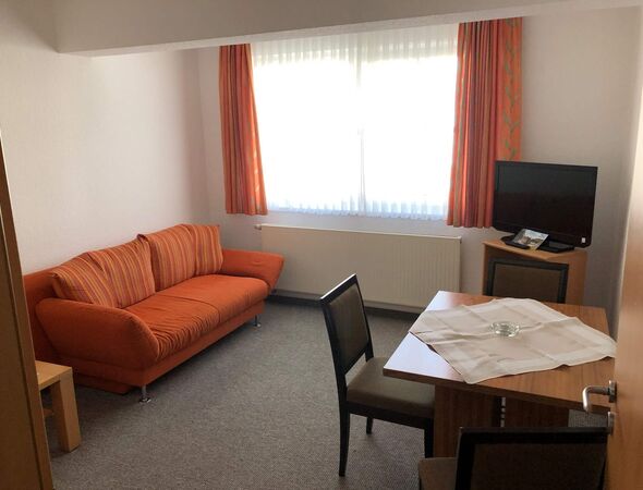 Appartment 70 Wohnbereich Couch Tich mit Stuhl und Fernseher