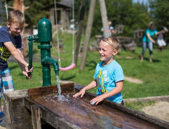 Kinderspielplatz Kinder an der Wasserpumpe